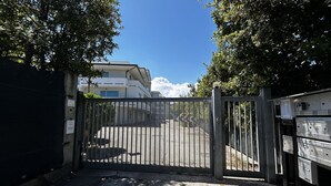 A gated entrance to a building with a parking area visible beyond the gate. - [50m from the Beach] Modern Studio with WiFi & A/C (Lido Di fermo)