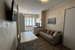 A compact living space with a kitchenette, a dining area, and a sofa.