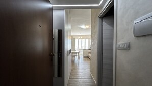 A hallway with a door, a light switch, and a wall-mounted thermostat. - [50m from the Beach] Modern Studio with WiFi & A/C (Lido Di fermo)