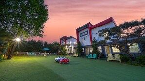 A residential area with two-story houses, a green lawn, and a red convertible car parked on the grass. - Yangpyeong Dodam Dodam Pension (Yangpyeong)
