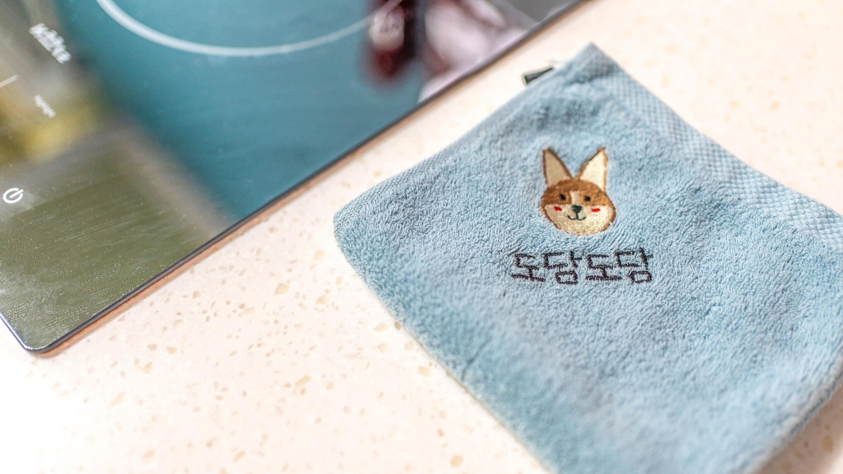 A laptop with a blue cloth featuring a rabbit and Japanese characters on a speckled countertop.