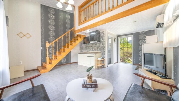 A modern living space with a staircase, kitchen, dining area, and a TV. - Yangpyeong Dodam Dodam Pension (Yangpyeong)