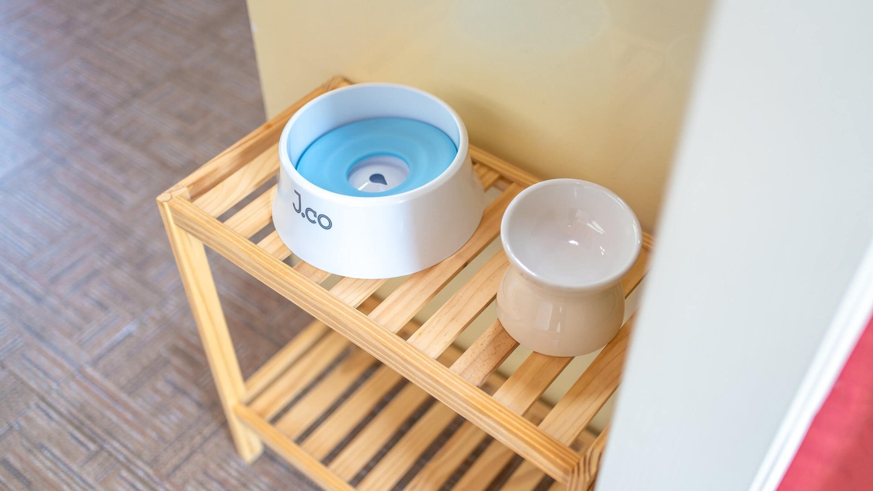 A small wooden stool with a white and blue object on it and a white cup beside it.