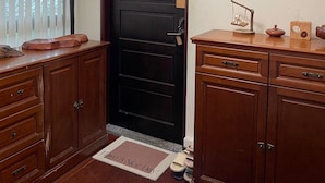 Une porte en bois avec un trou de serrure, un paillasson portant un message et une petite étagère avec une horloge et un objet décoratif.