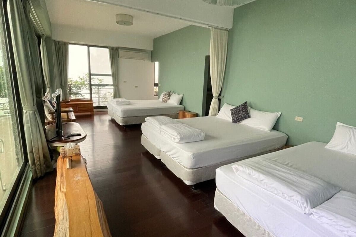 A hotel room with two beds, a wooden sculpture, and a large window with curtains.