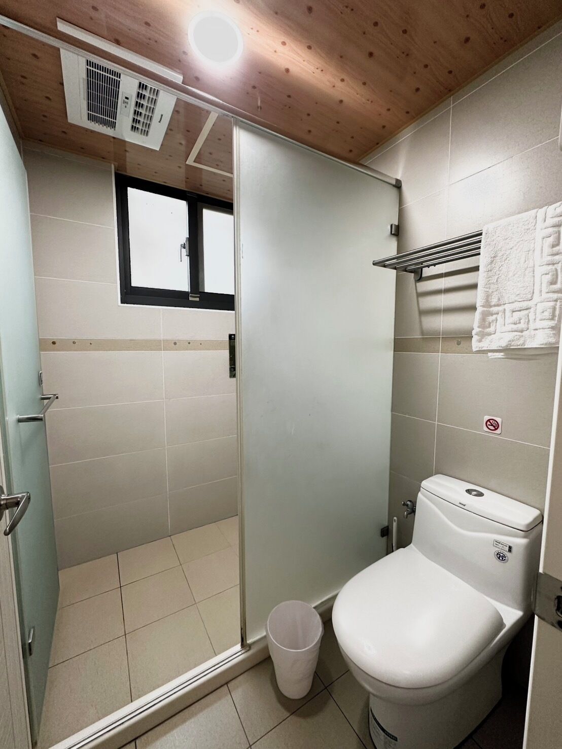 Un baño pequeño con inodoro, cabina de ducha y ventana.