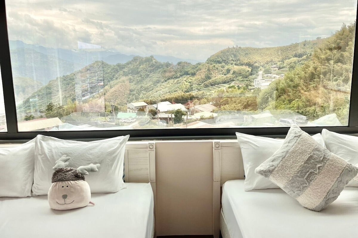 A room with a bed and a window overlooking a mountainous landscape.
