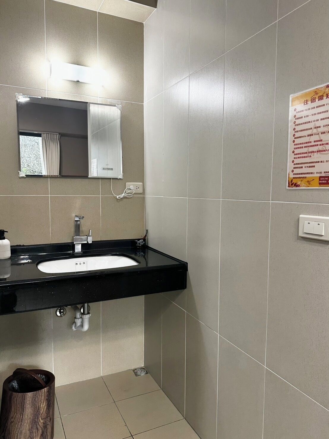 A bathroom with a black sink, a mirror, and a poster on the wall.