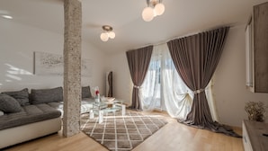 Un salon moderne avec un canapé, une table basse en verre, un tapis et un pilier en pierre.