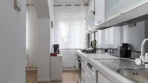 Eine moderne Küche mit eingebautem Geschirrspüler, einer Edelstahl-Spüle und einer Kaffeemaschine auf der Arbeitsfläche.