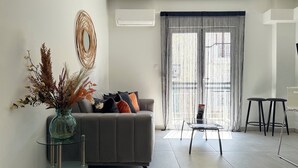 A modern living room with a grey sofa, a glass coffee table, and a vase with dried plants. - P7 - 2 Bedrooms Jacuzzi Rooftop (Athens)