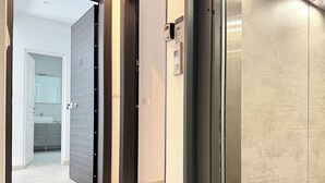 A modern interior with a hallway leading to a bathroom, featuring a door with a keycard lock and a wall-mounted intercom. - P7 - 2 Bedrooms Jacuzzi Rooftop (Athens)