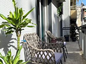 Wicker chairs with cushions on a balcony, a potted plant, and a water spigot. - P7 - 2 Bedrooms Jacuzzi Rooftop (Athens)