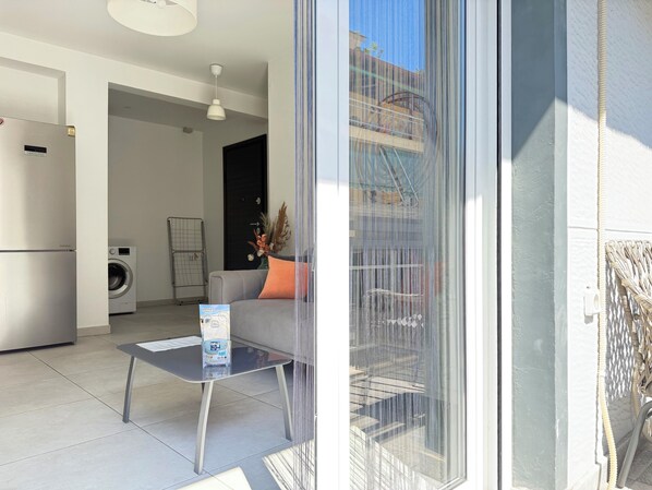 A modern apartment with a kitchen, a washing machine, a sofa with a cushion, and a table with a brochure. - P7 - 2 Bedrooms Jacuzzi Rooftop (Athens)