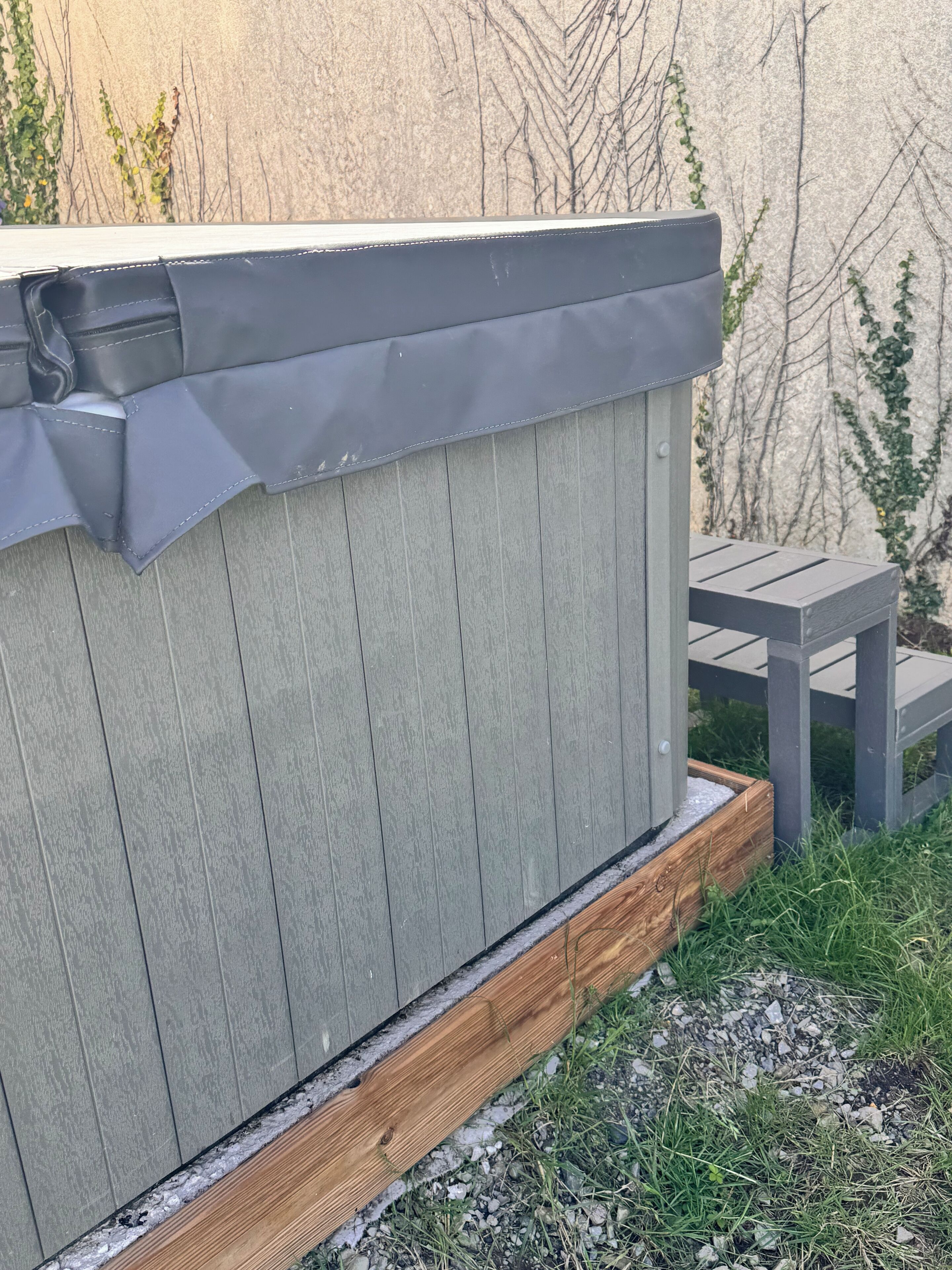 A wooden deck with a hot tub, a small table, and a wooden planter box.