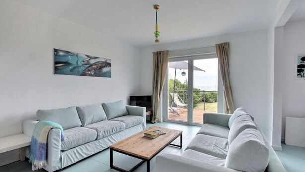 Ein modernes Wohnzimmer mit einer Couch, einem Couchtisch und einem Fernseher.