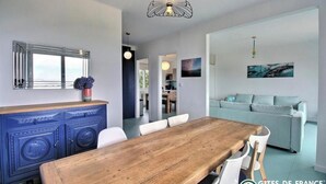 Ein modernes Wohnzimmer mit einem Holzessttisch, einer blauen Kommode, einem Sofa und einem großen Spiegel.