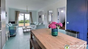 Ein modernes Wohnzimmer mit einem Holzesstisch, zwei Sofas und einem großen Fenster.