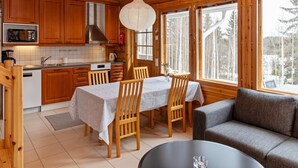 Ein Holzblockhaus-Innenraum mit Küche, Essbereich und Sitzgelegenheiten.