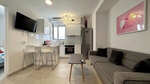 A modern living room with a grey sofa, a small coffee table, and a TV mounted on the wall. - P9 - 4 Bedroom apartments - Jacuzzi rooftop (Athens)