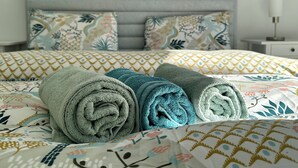 A neatly made bed with rolled towels, a patterned bedspread, and matching pillows. - P9 - 4 Bedroom apartments - Jacuzzi rooftop (Athens)