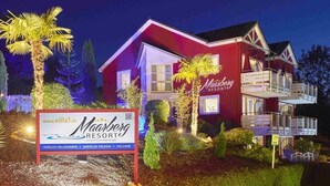 Um edifício de dois andares vermelho e branco com varandas, identificado como 'Maareberg Resort'.