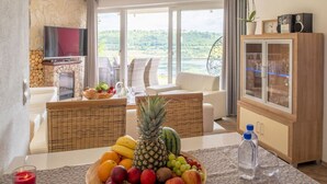 Uma área de refeições com uma fruteira, uma garrafa de água e uma televisão.