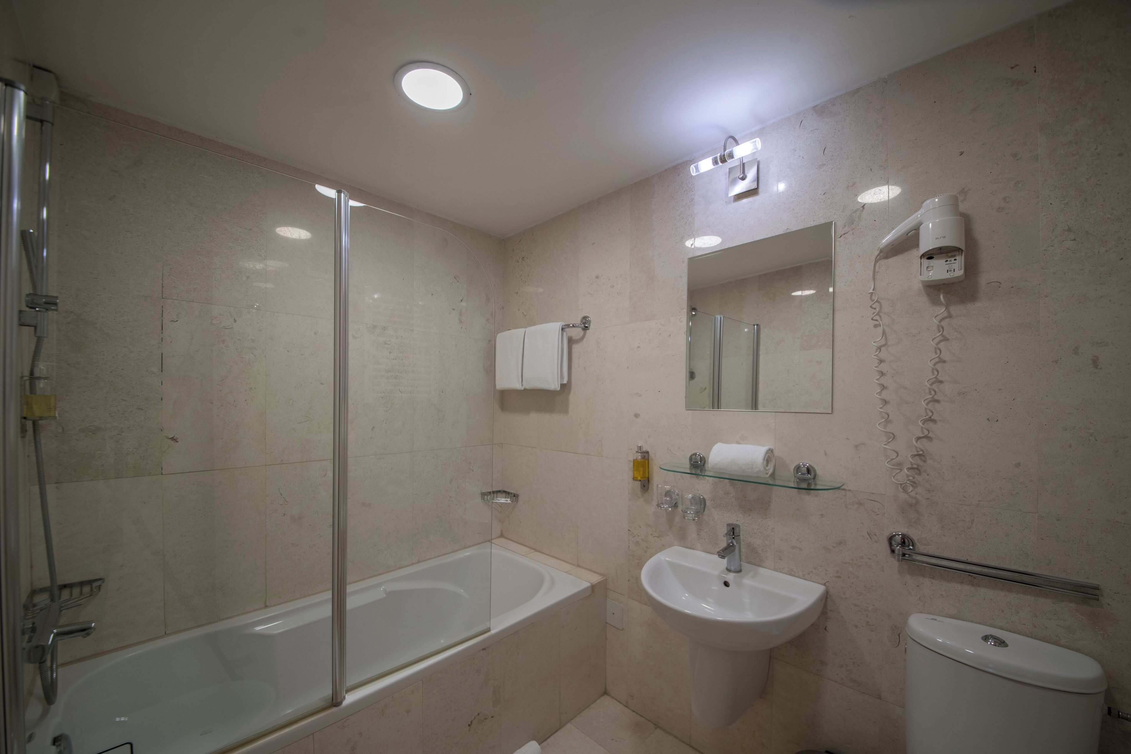Une salle de bain moderne avec une douche à parois de verre, une baignoire blanche, un lavabo et des toilettes.