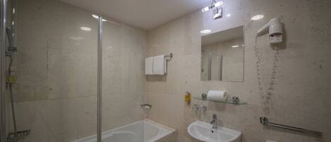 Un baño moderno con ducha envuelta en vidrio, una bañera blanca, un lavabo y un inodoro.
