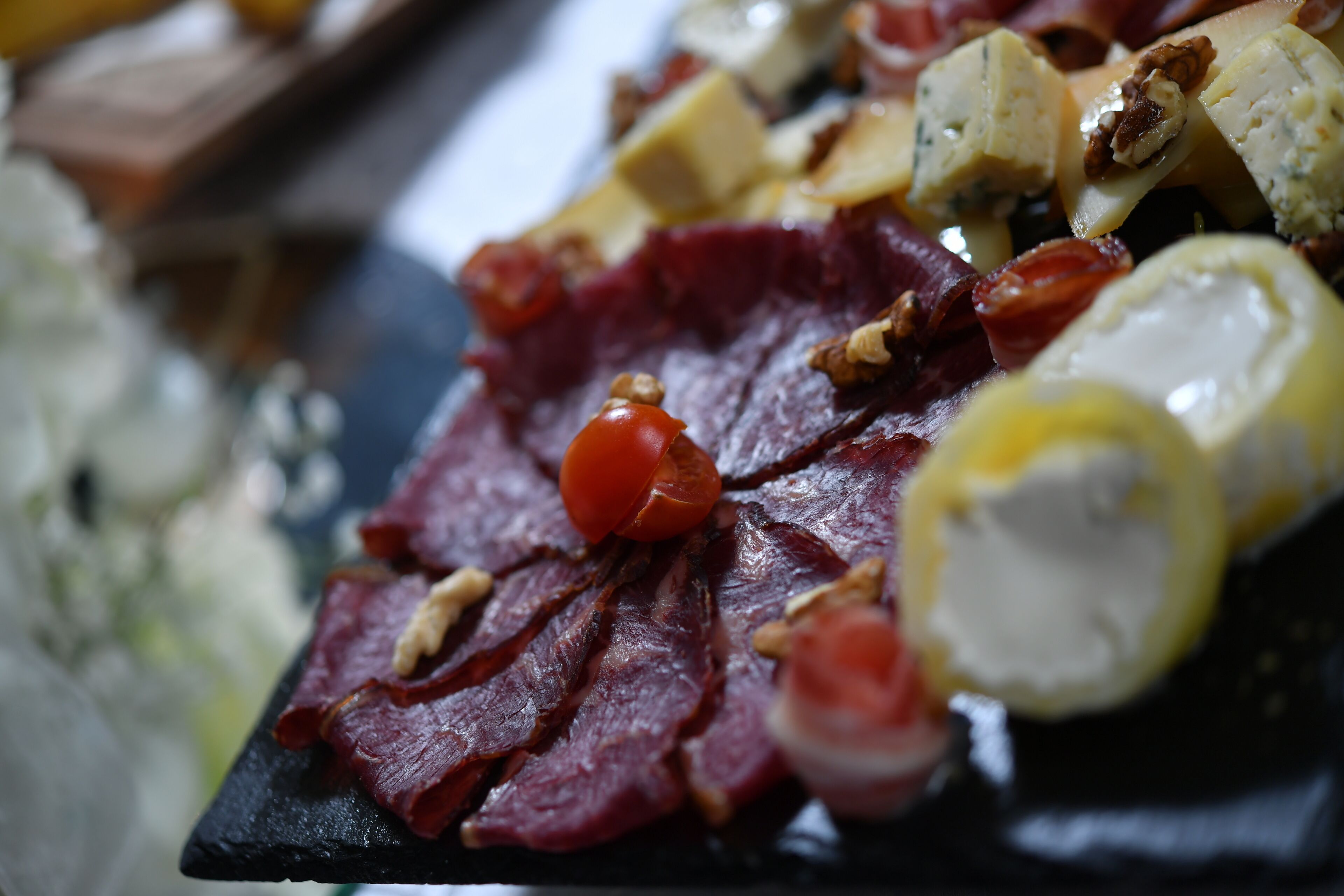 A charcuterie board with various meats, cheeses, and nuts.