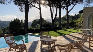 Eine Holzterrasse mit Korbmöbeln und einem Pool.