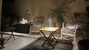 Ein gemütlicher Außenbereich mit Korbmöbeln, einem Tisch und einer Lampe.