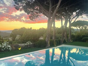 Piscina con vistas al atardecer, rodeada de árboles y follaje.