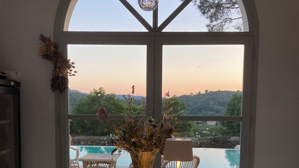 Ein Esstisch für zwei Personen, mit Blick auf einen Swimmingpool und die umliegende Natur.