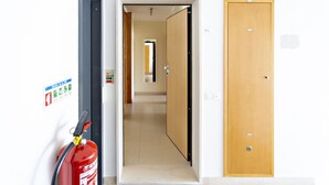 A hallway with a fire extinguisher, a wooden door, and a wall-mounted sign.