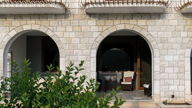 A stone building with two arched doorways leading to a patio area with outdoor furniture. - Apartment Frankie's Place (Dubrovnik)