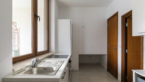 A compact kitchen with a double sink, a refrigerator, and wooden doors. - Apartment Frankie's Place (Dubrovnik)