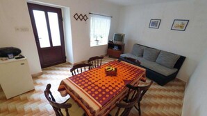 A compact living space with a dining table, chairs, a sofa, a television, and a refrigerator. - Holiday Home Katarina (Vinodol)