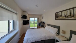 A bedroom with two beds, a TV, a desk, and a painting. - Studio | Sleeps 3 | Mountain Views - 5 Mins from Kenmare town. (Kenmare)