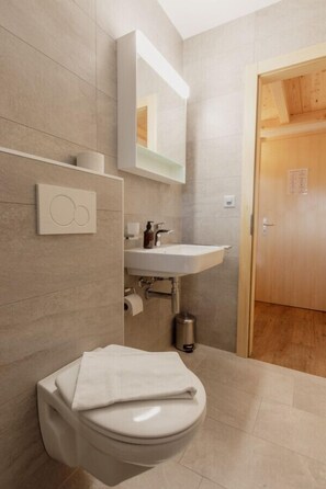 Une salle de bain moderne avec des toilettes, un lavabo et un miroir.