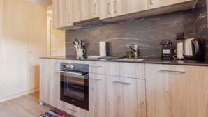 A modern kitchen with wooden cabinets, a black countertop, and stainless steel appliances. - Studio Rénové à Grimentz (Grimentz)