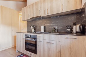Une cuisine moderne avec des meubles en bois, un plan de travail noir et des appareils électroménagers en acier inoxydable.