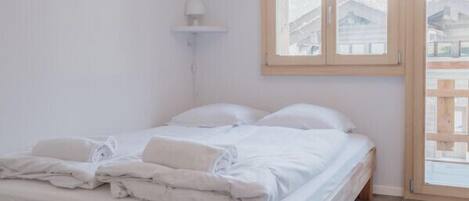 Een slaapkamer met een houten bed, een raam en uitzicht op de omgeving.