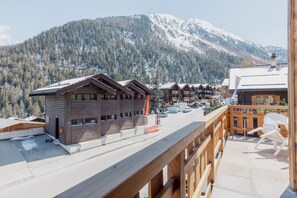 Un chalet en bois doté d’un balcon donnant sur une montagne enneigée.