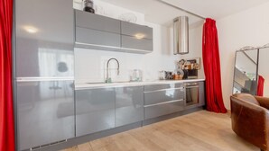 A modern kitchen with grey cabinets, stainless steel appliances, and a red curtain.