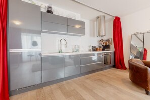 Una cocina moderna con gabinetes grises, electrodomésticos de acero inoxidable y una cortina roja.