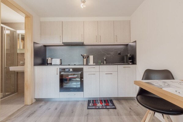 Una cocina compacta con horno integrado, cafetera y una pequeña superficie de encimera.