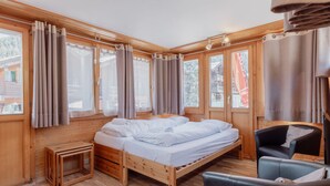 Una habitación tipo cabaña de madera con una cama, una silla y una mesita.
