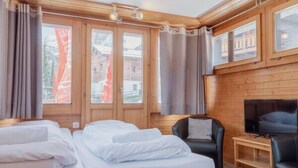 Una habitación con dos camas de madera, una televisión y una silla.