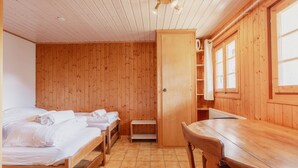 Une pièce en bois avec deux lits, une table en bois et une armoire.